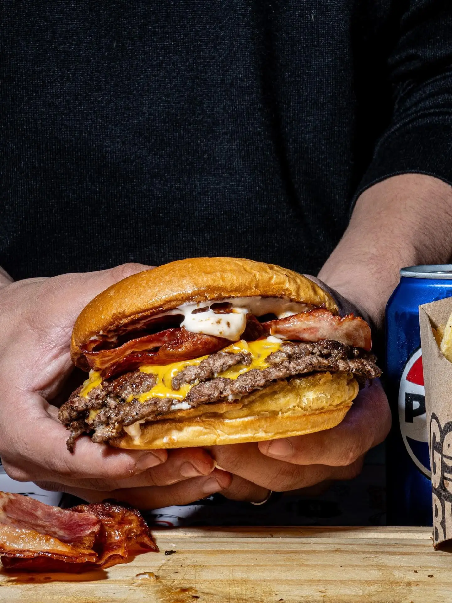 Burger doble carne con bacon y cheddar derretido frente a una lata
