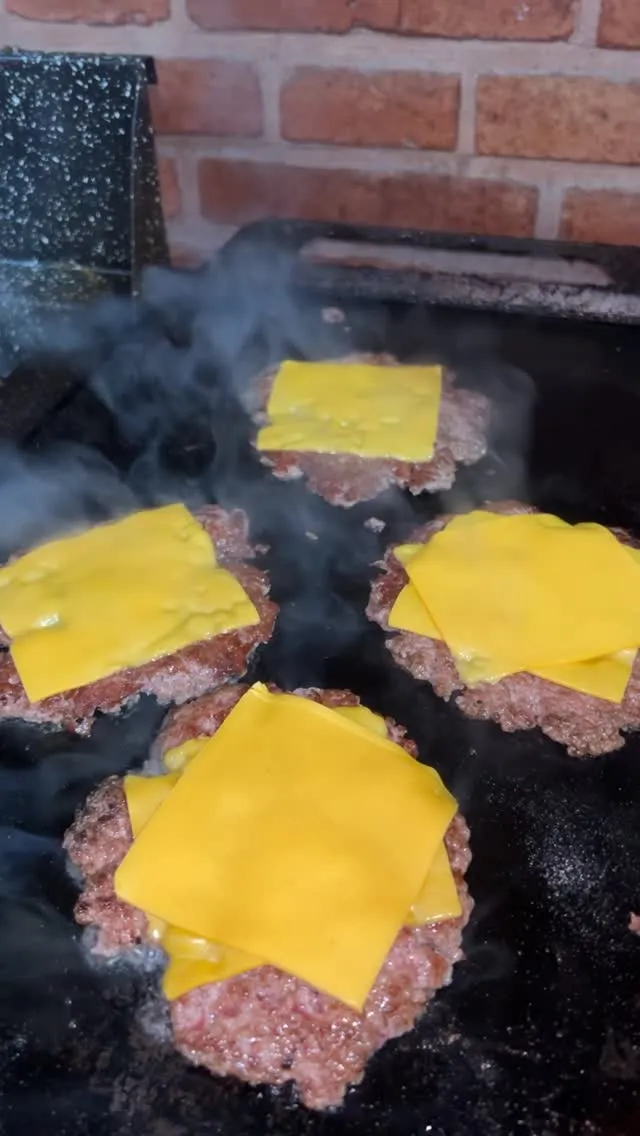 Medallones de carne smasheándose en la plancha con cheddar derritiéndose